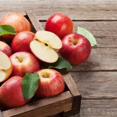 Skrzynka pełna soczystych jabłek, niektóre przekrojone, ukazujące wnętrze. Czy pies może jeść jabłko? Tak, ale bez pestek!